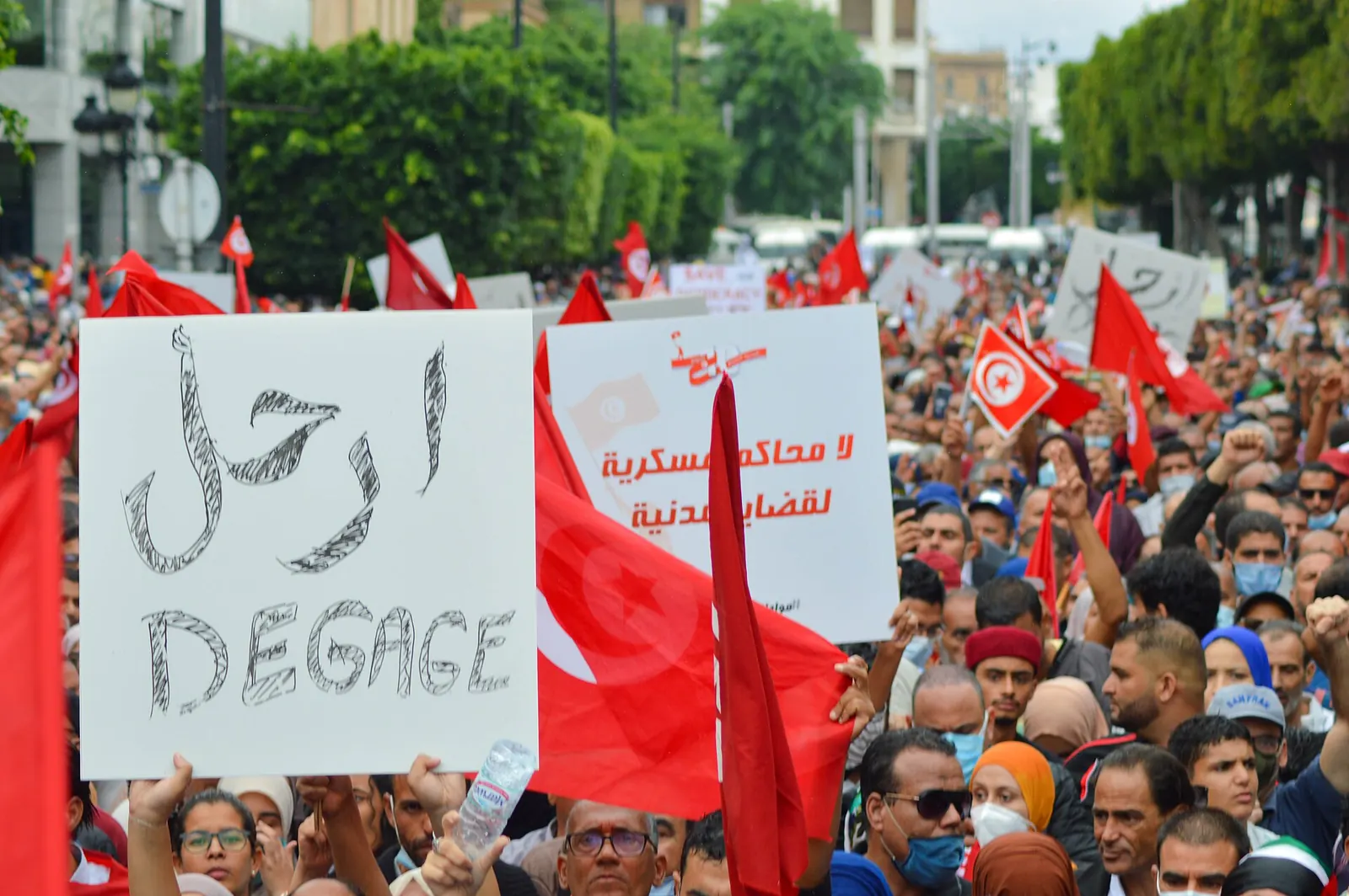 لافتة «ارحل – Dégage» مرفوعة في وجه قيس سعيد وسط الأعلام التونسية، خلال مظاهرة ضد تركيز السلطات في تونس العاصمة، 10 أكتوبر 2021